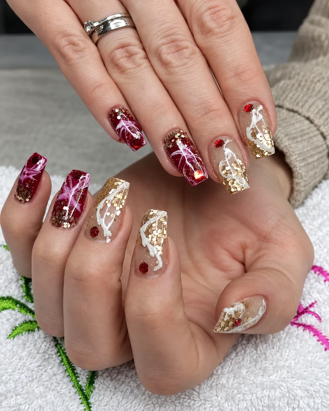 Nageldesign aus dem Studio: Bordeaux und Goldglitzer mit weißen Schnörkeln